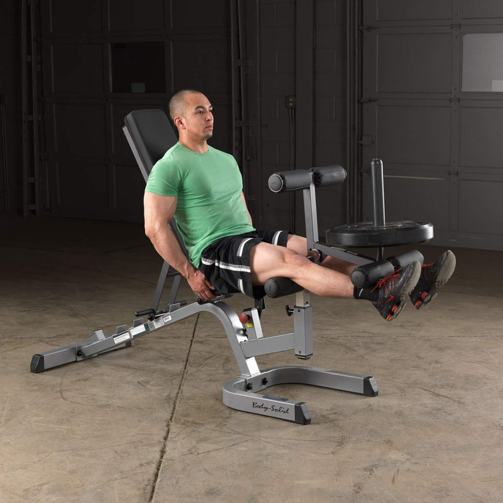 Body-Solid Flat Incline Decline Bench GFID71B Man doing leg extensions with plate-loaded Body-Solid workout bench