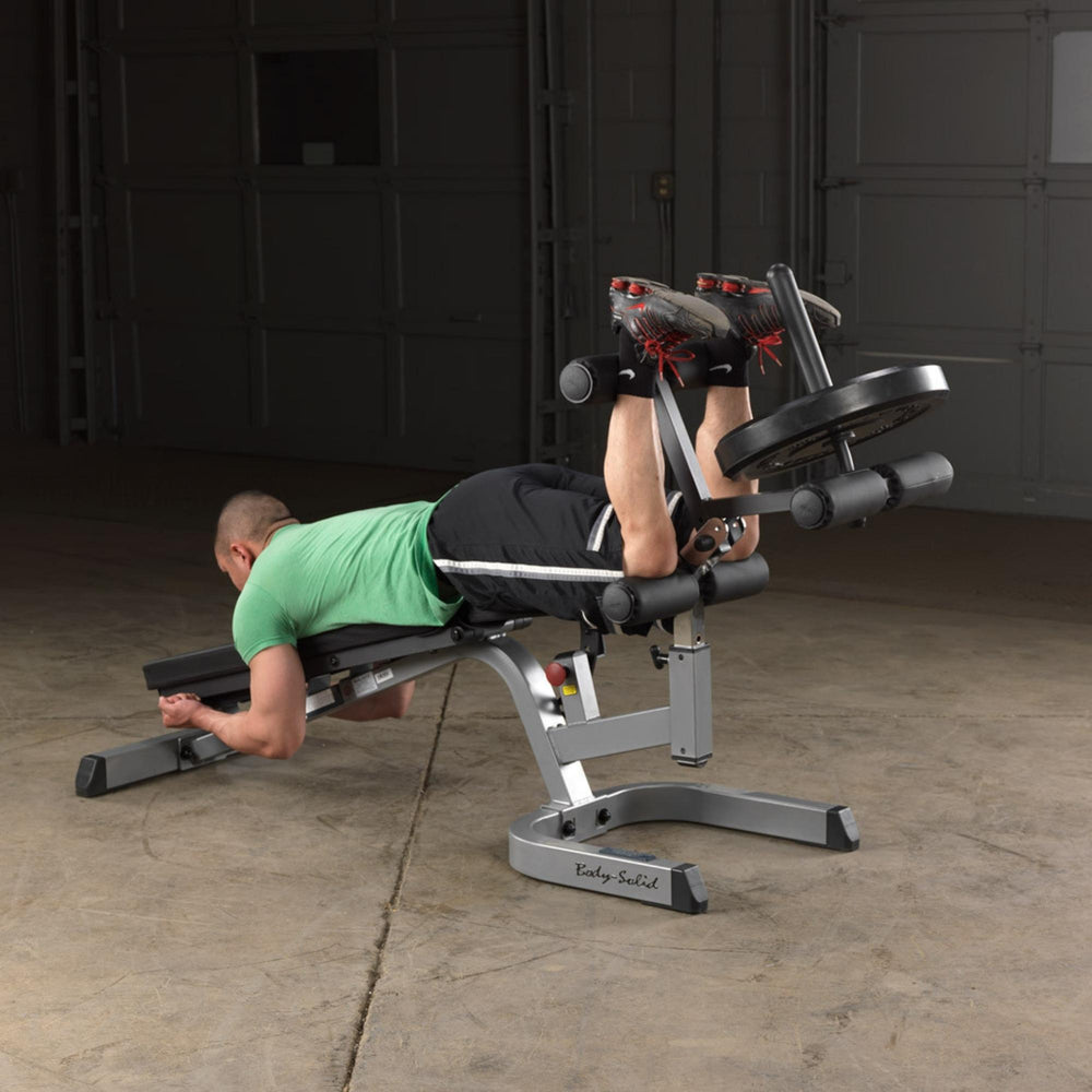 Body-Solid Flat Incline Decline Bench GFID71B Man performing lying leg curls with weight plate on Body-Solid bench