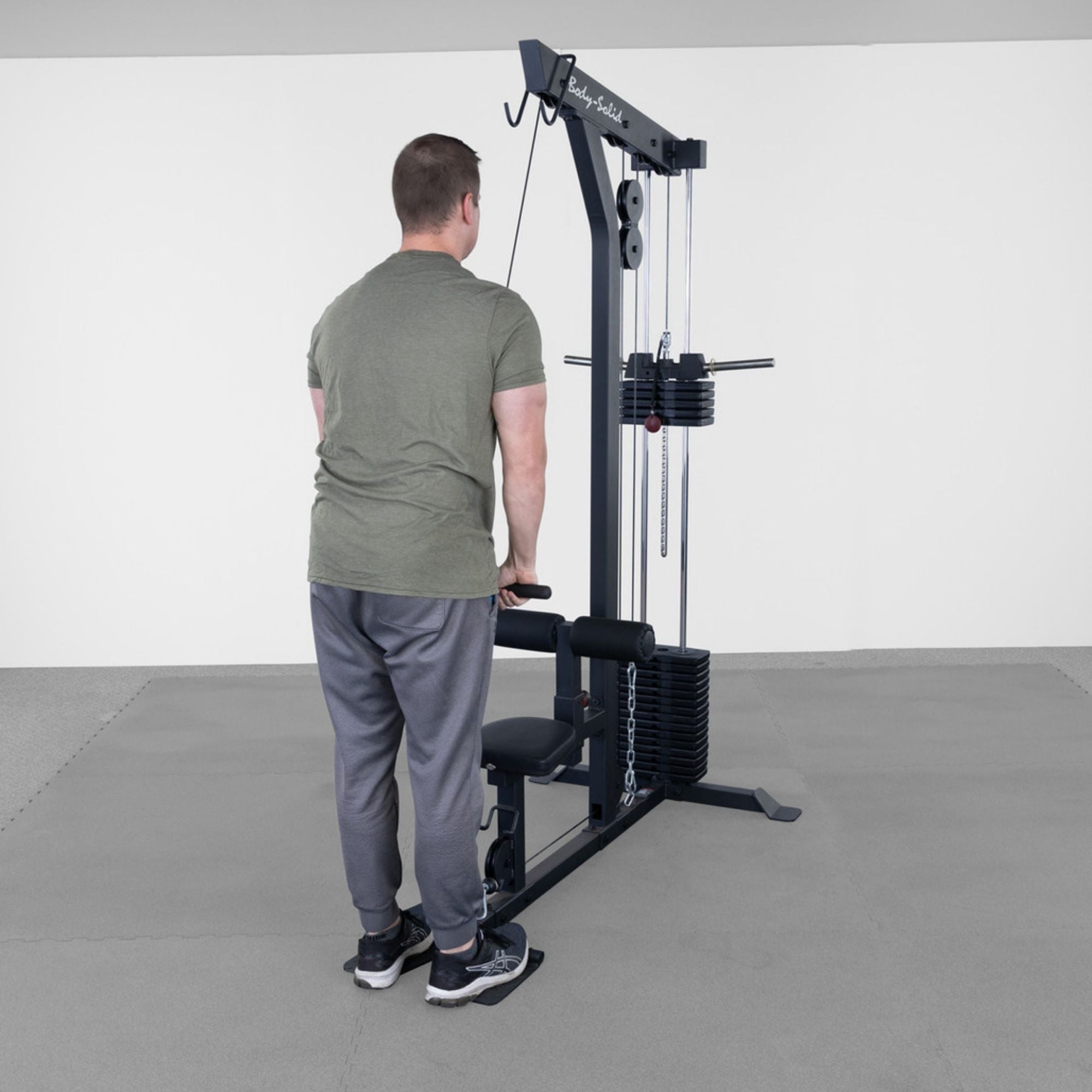 Body-Solid Lat Machine With Weight Stack GLM85B Man doing standing tricep pushdowns