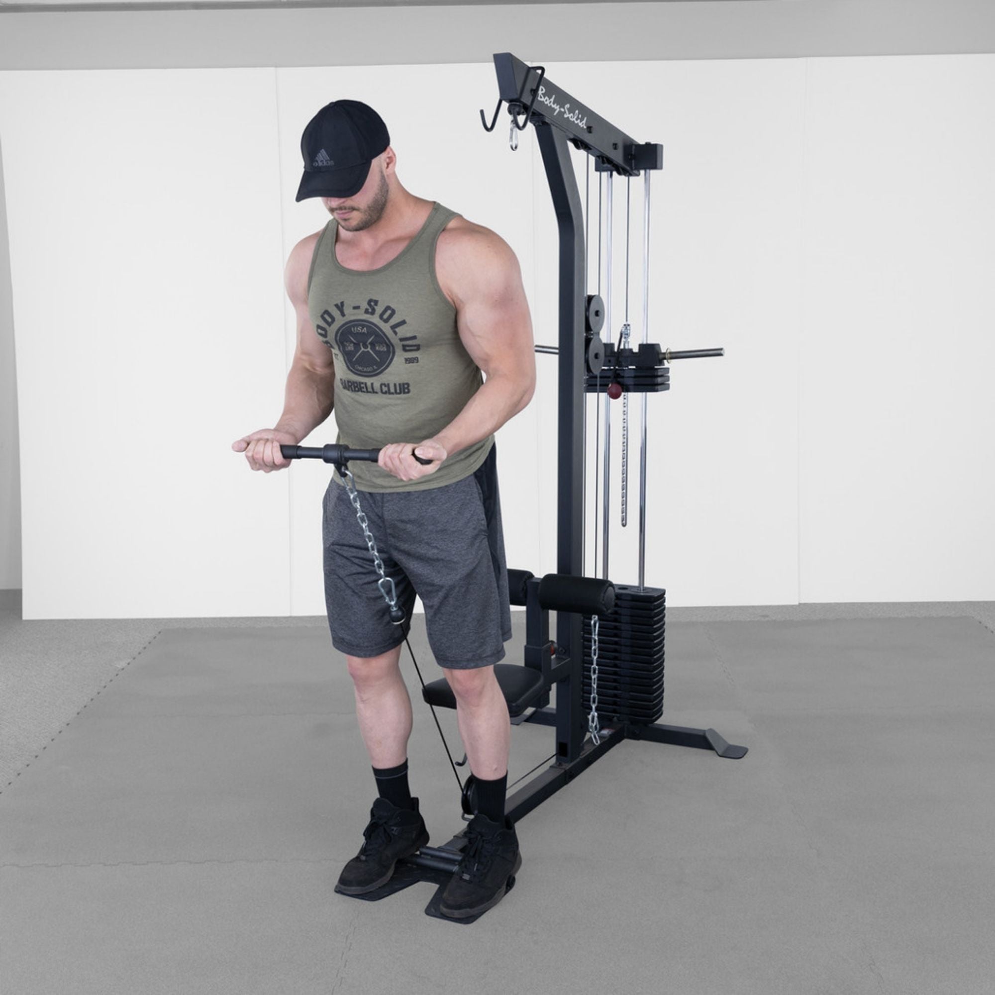 Body-Solid Lat Machine With Weight Stack GLM85B Man performing standing bicep curls