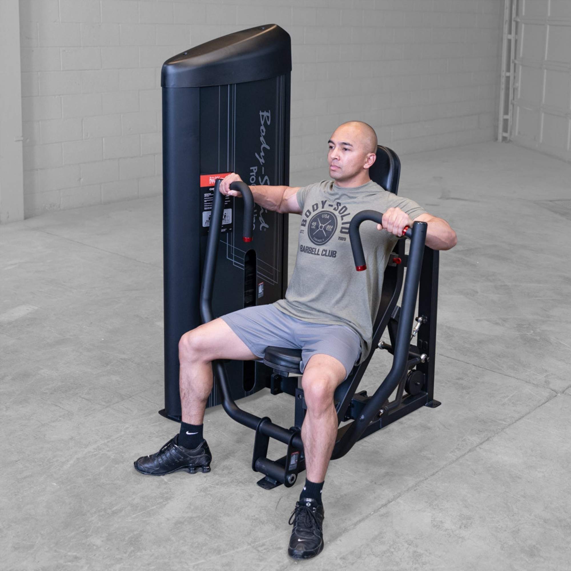 Body-Solid PCL2 Chest Press S2CPX Man performing chest press exercise on a Body-Solid Pro Club Line machine, arms extended and back supported by the seat.