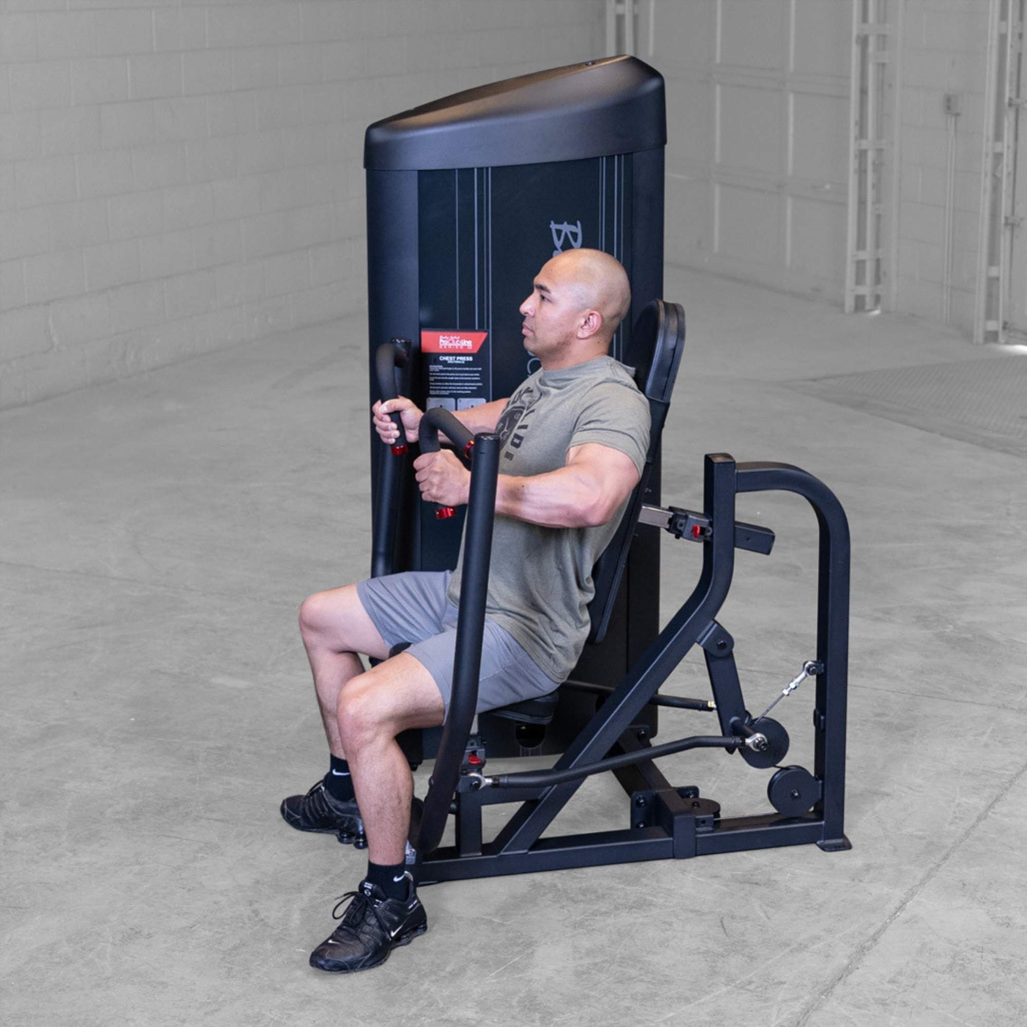 Body-Solid PCL2 Chest Press S2CPX Man using a Body-Solid Pro Club Line chest press machine, seated and pressing the handles forward in a gym.