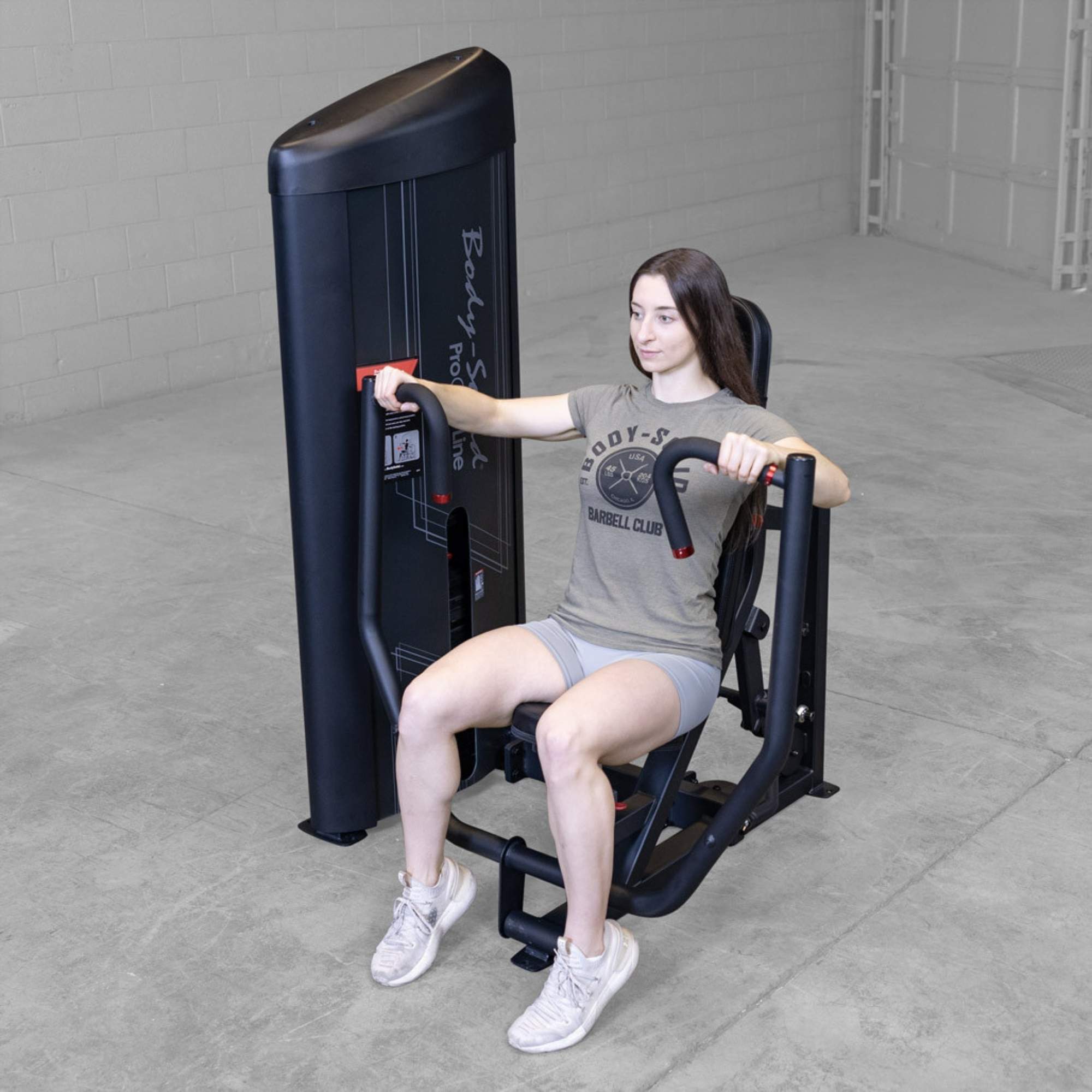 Body-Solid PCL2 Chest Press S2CPX Woman exercising on a Body-Solid Pro Club Line chest press machine, mid-rep with arms partially extended
