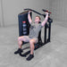 Body-Solid PCL2 Multi Press S2MPX Man performing seated on a shoulder press machine pushing handles upward in a gym setting
