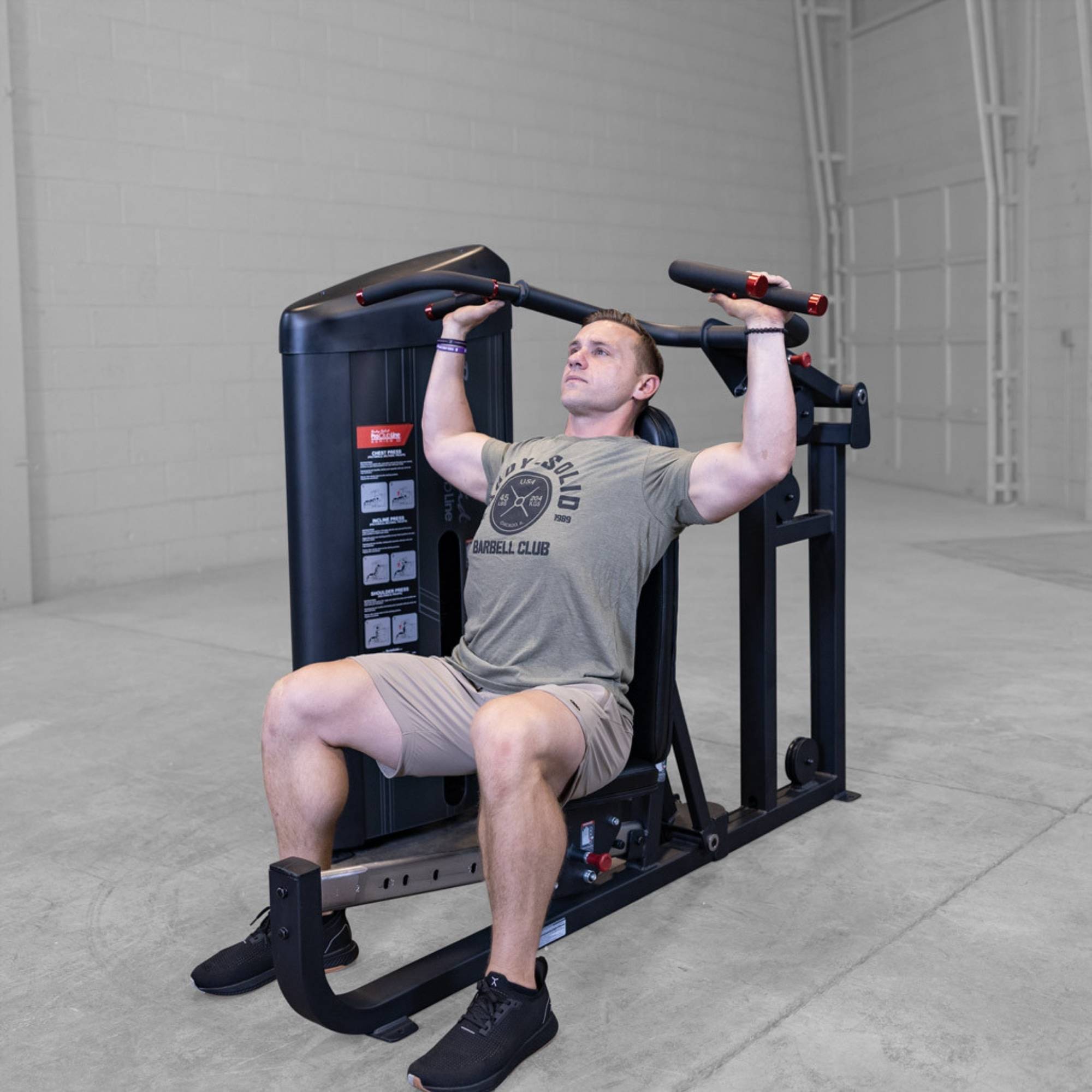 Body-Solid PCL2 Multi Press S2MPX Man seated pressing overhead on the machine while wearing a gray shirt