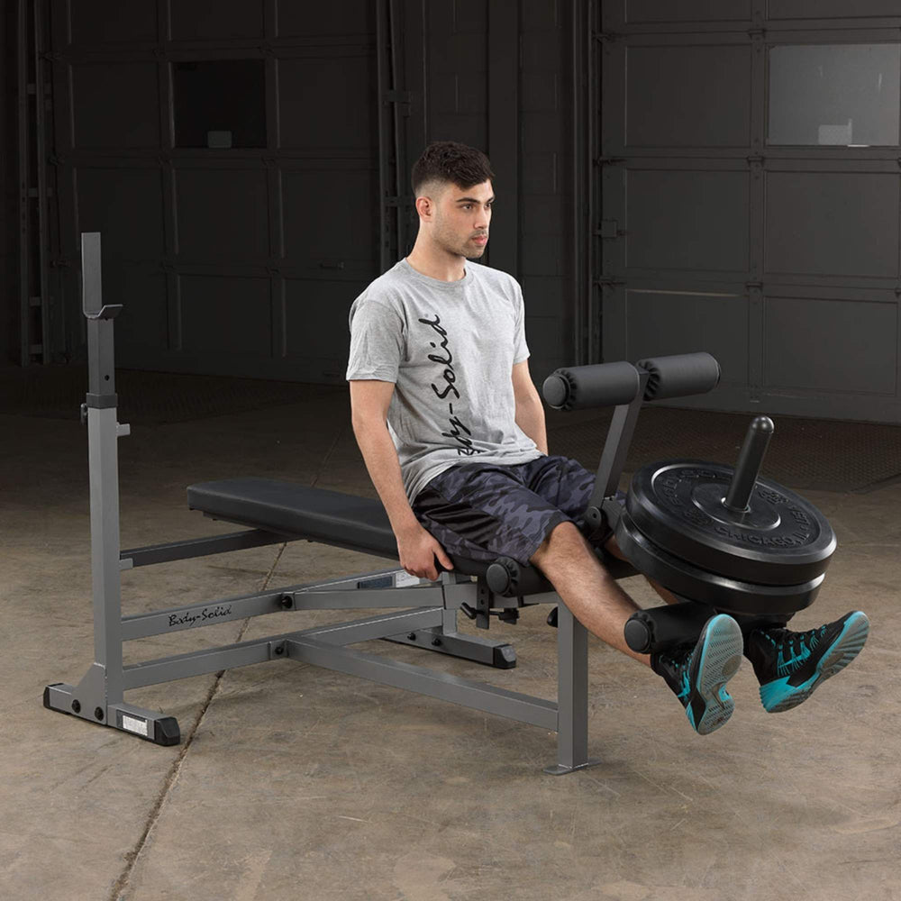 Body-Solid Powercenter Rack Bench Combo GDIB46LB Man executing leg extension exercise with weights on Body-Solid bench