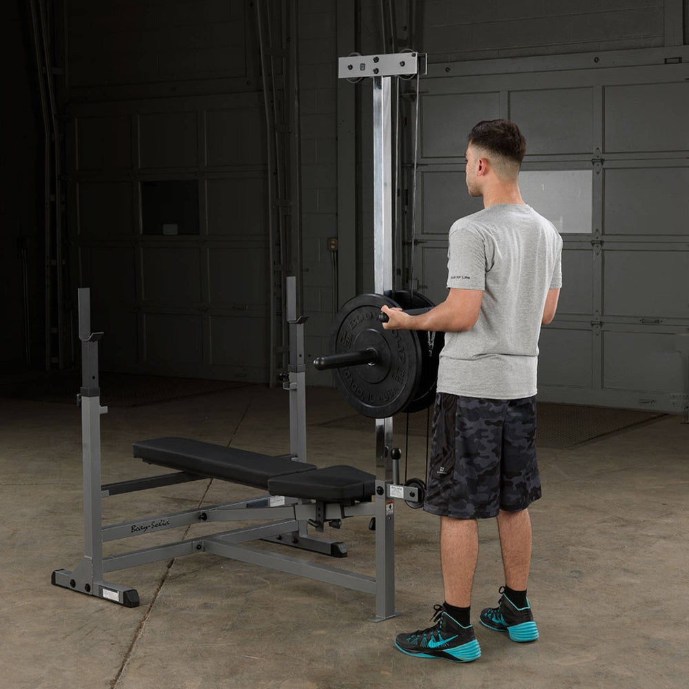 Body-Solid Powercenter Rack Bench Combo GDIB46LB Man loading weight plates onto Body-Solid lat attachment
