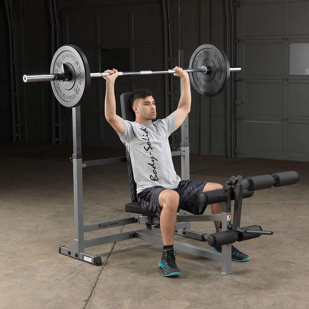 Body-Solid Powercenter Rack Bench Combo GDIB46LB Man performing overhead shoulder press with barbell on Body-Solid adjustable bench