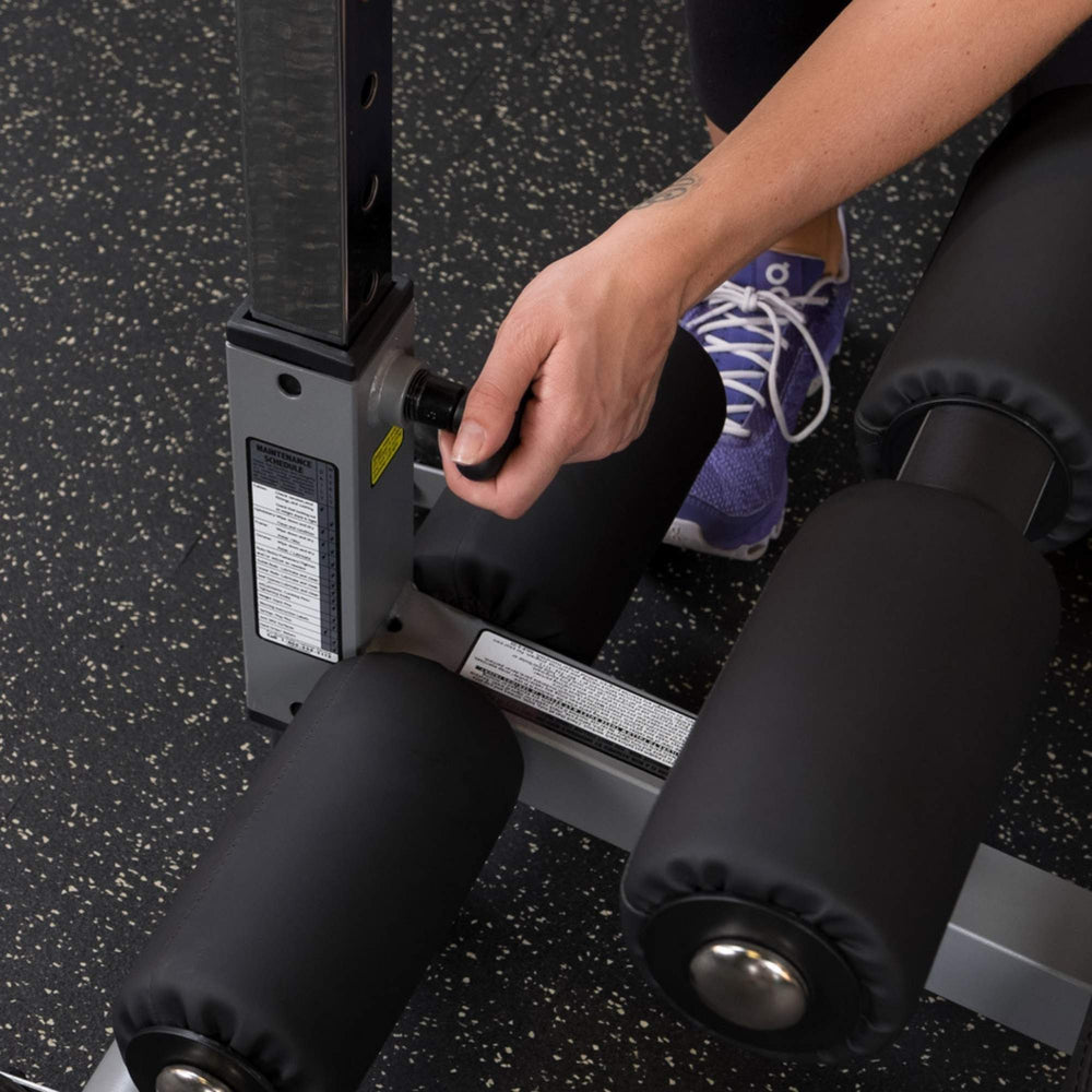 Body-Solid Pro-Style Adjustable Ab Board GAB60B Close-up of hand adjusting locking pin on decline bench support