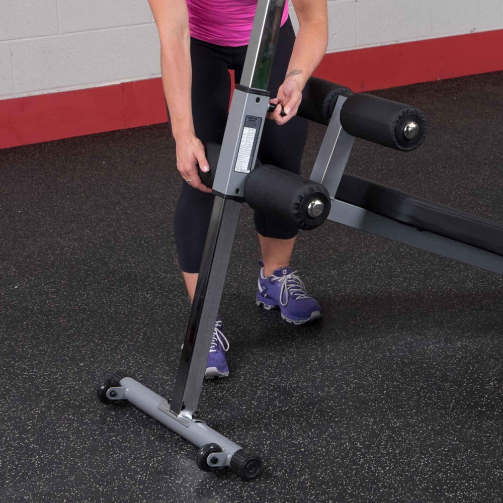 Body-Solid Pro-Style Adjustable Ab Board GAB60B Woman adjusting support height on vertical support bar of sit-up bench