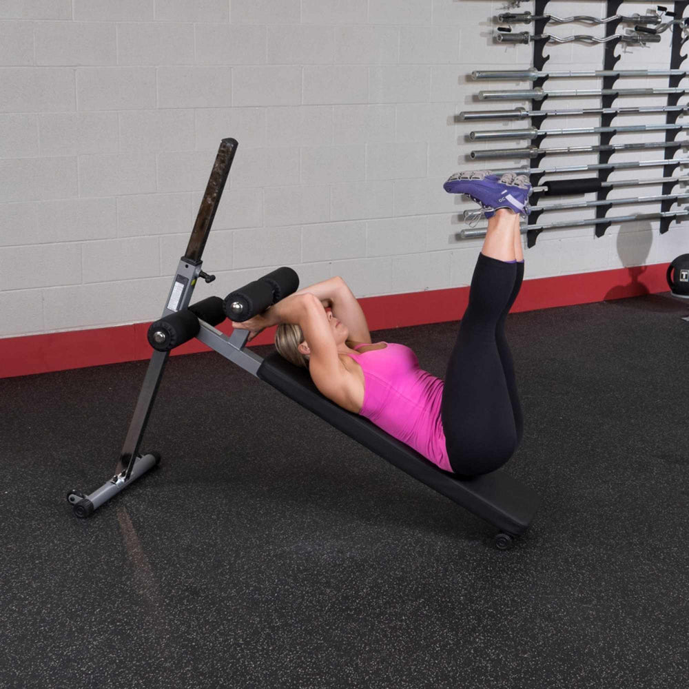 Body-Solid Pro-Style Adjustable Ab Board GAB60B Woman performing leg raise with hands behind head on ab bench