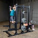 Body-Solid Pro ClubLine Double Half Rack SPR500DBL Dual training view — woman bench pressing and man squatting on Body-Solid SPR500DBL half rack system with loaded Olympic bars.
