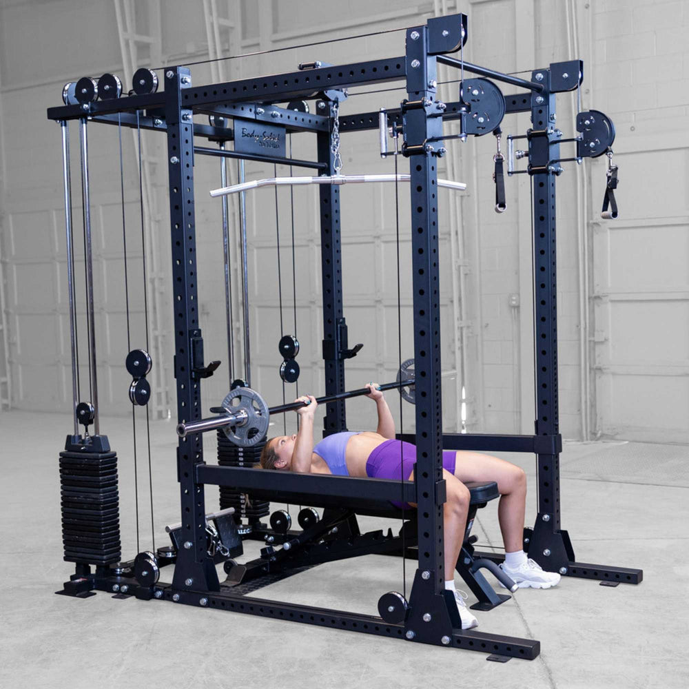 Body-Solid Pro ClubLine Functional Trainer Attachment SPRFTS Woman executing flat barbell bench press inside Body-Solid Pro ClubLine SPRFTS power rack functional trainer.
