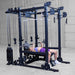 Body-Solid Pro ClubLine Functional Trainer Attachment SPRFTS Woman executing flat barbell bench press inside Body-Solid Pro ClubLine SPRFTS power rack functional trainer.
