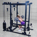 Body-Solid Pro ClubLine Functional Trainer Attachment SPRFTS Woman performing barbell squat inside Body-Solid Pro ClubLine SPRFTS functional trainer power rack, wearing purple workout outfit.
