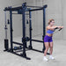 Body-Solid Pro ClubLine Functional Trainer Attachment SPRFTS Woman standing behind Body-Solid Pro ClubLine SPRFTS trainer preparing for barbell triceps pushdown.

