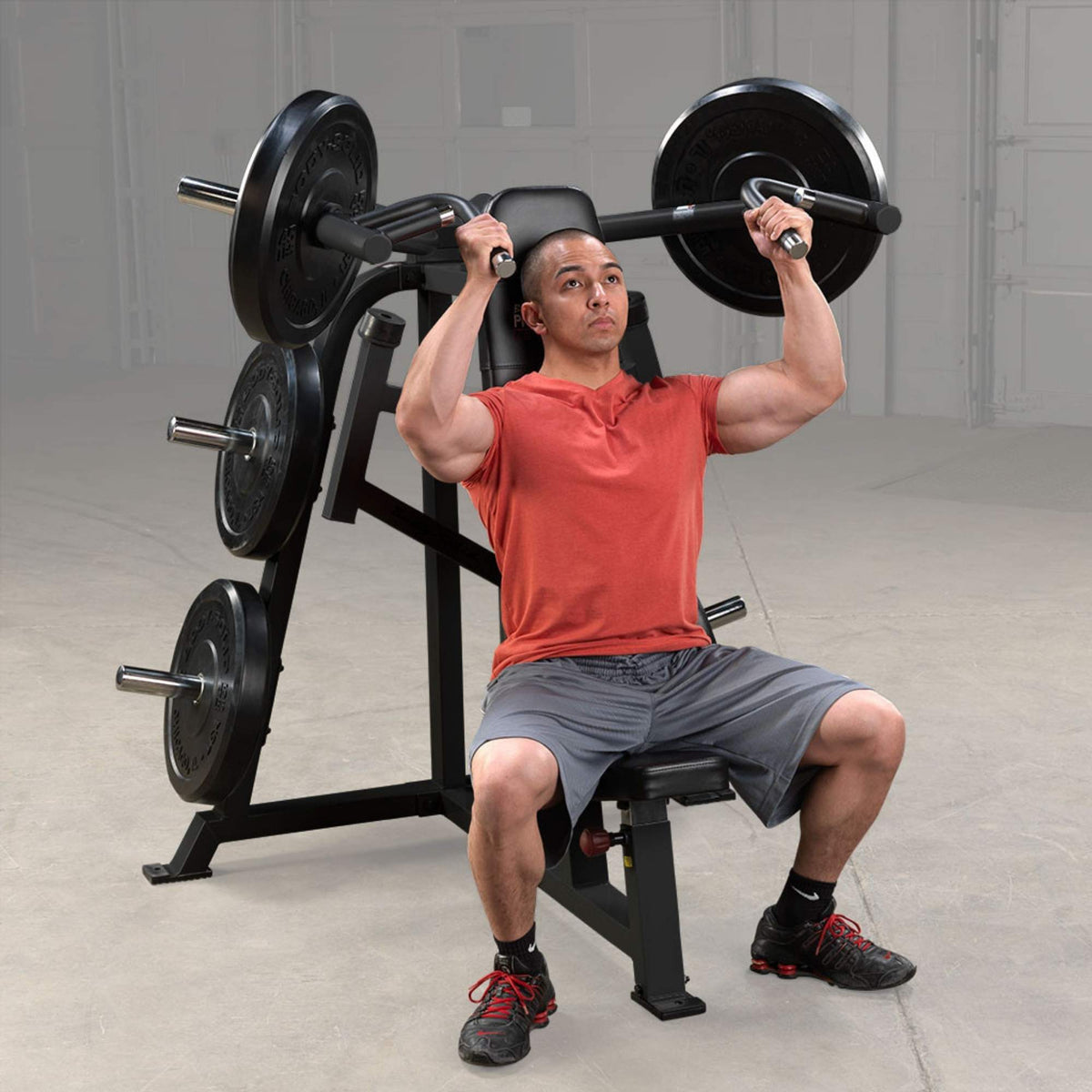 Body-Solid Pro ClubLine LVSP Leverage Shoulder Press LVSPB Man performing overhead press exercise on Body-Solid LVSP Leverage Shoulder Press machine with loaded Olympic plates.
