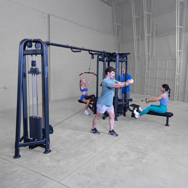 Body-Solid Pro ClubLine SJG Jungle Gym SJG500 Man performing chest flys on cable machine while others do seated row and lat pulldown on multi-station gym system.
