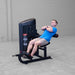 Body-Solid Pro ClubLine Series 2 Ab and Back S2ABBX Man doing seated leg extension with arms crossed using Body-Solid ProClubLine machine in a gym.