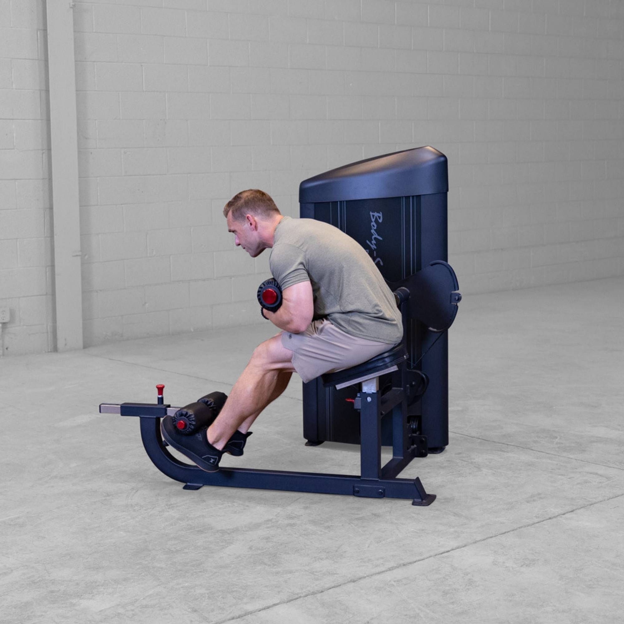 Body-Solid Pro ClubLine Series 2 Ab and Back S2ABBX Side view of man executing seated ab crunch on Body-Solid ProClubLine commercial fitness machine with padded rollers.
