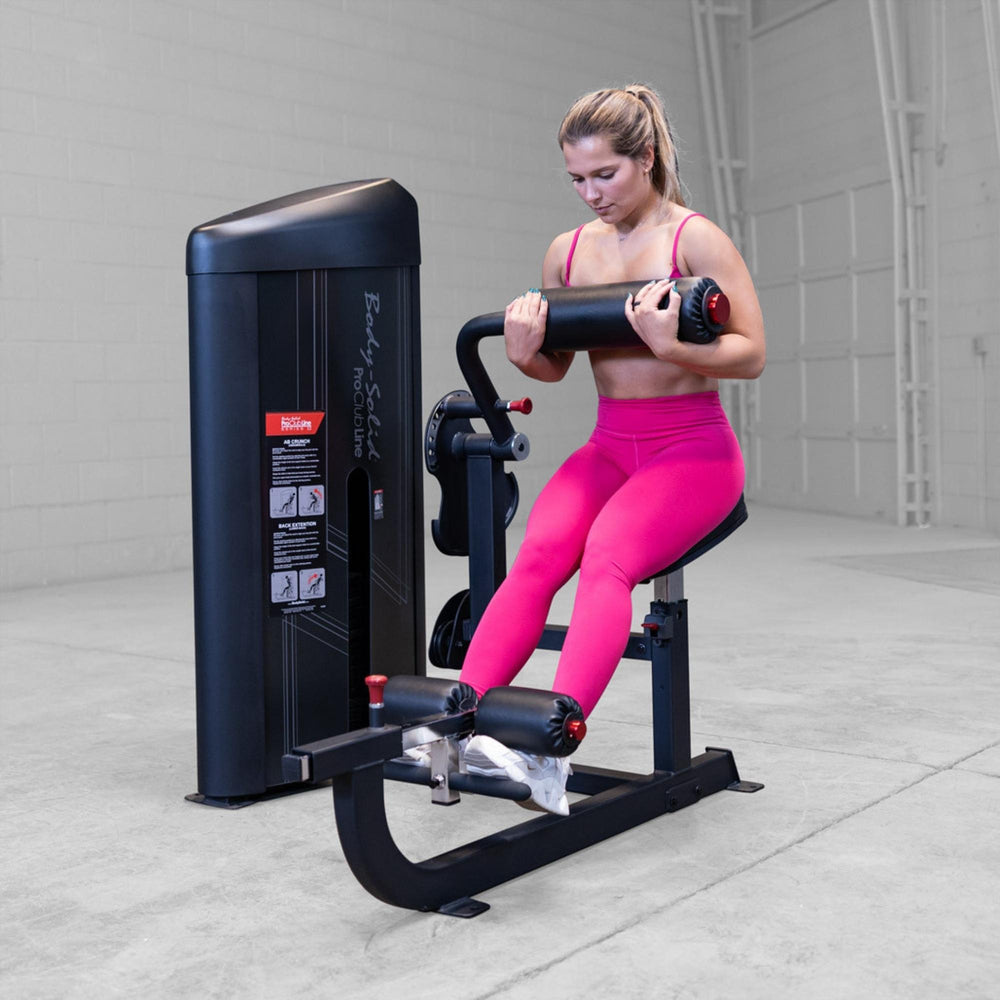 Body-Solid Pro ClubLine Series 2 Ab and Back S2ABBX Woman completing leg curl movement on Body-Solid ProClubLine lower body workout machine with padded rollers.
