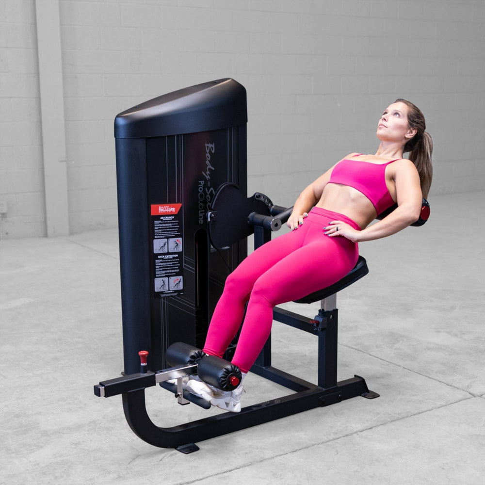 Body-Solid Pro ClubLine Series 2 Ab and Back S2ABBX Woman performing seated leg extensions leaning back on a Body-Solid leg machine for quadriceps activation.
