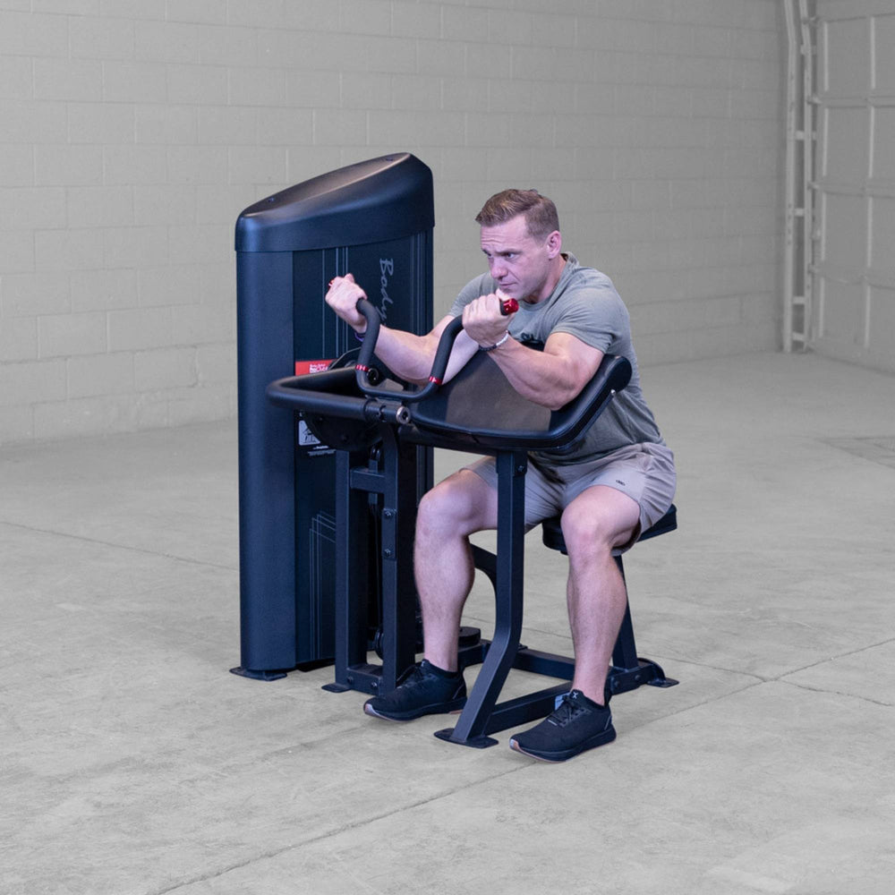 Body-Solid Pro ClubLine Series 2 Arm Curl S2ACX Man leaning into preacher pad while performing bicep curls on Body-Solid ProClubLine arm curl equipment.

