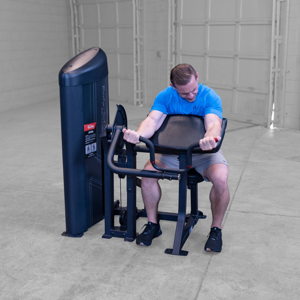Body-Solid Pro ClubLine Series 2 Arm Curl S2ACX Man performing seated arm curls on a Body-Solid ProClubLine preacher curl machine in a gym.
