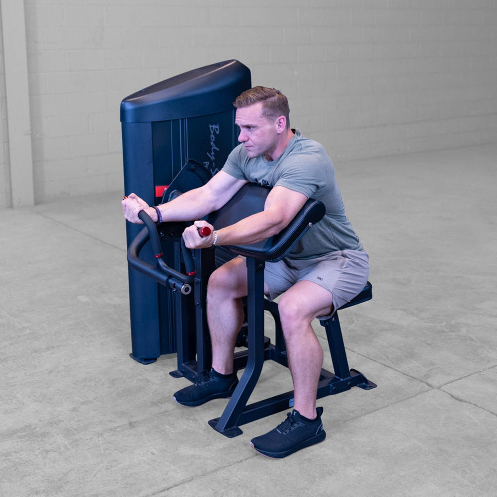Body-Solid Pro ClubLine Series 2 Arm Curl S2ACX Man seated and engaging in isolated bicep curl exercise on Body-Solid ProClubLine arm curl machine.