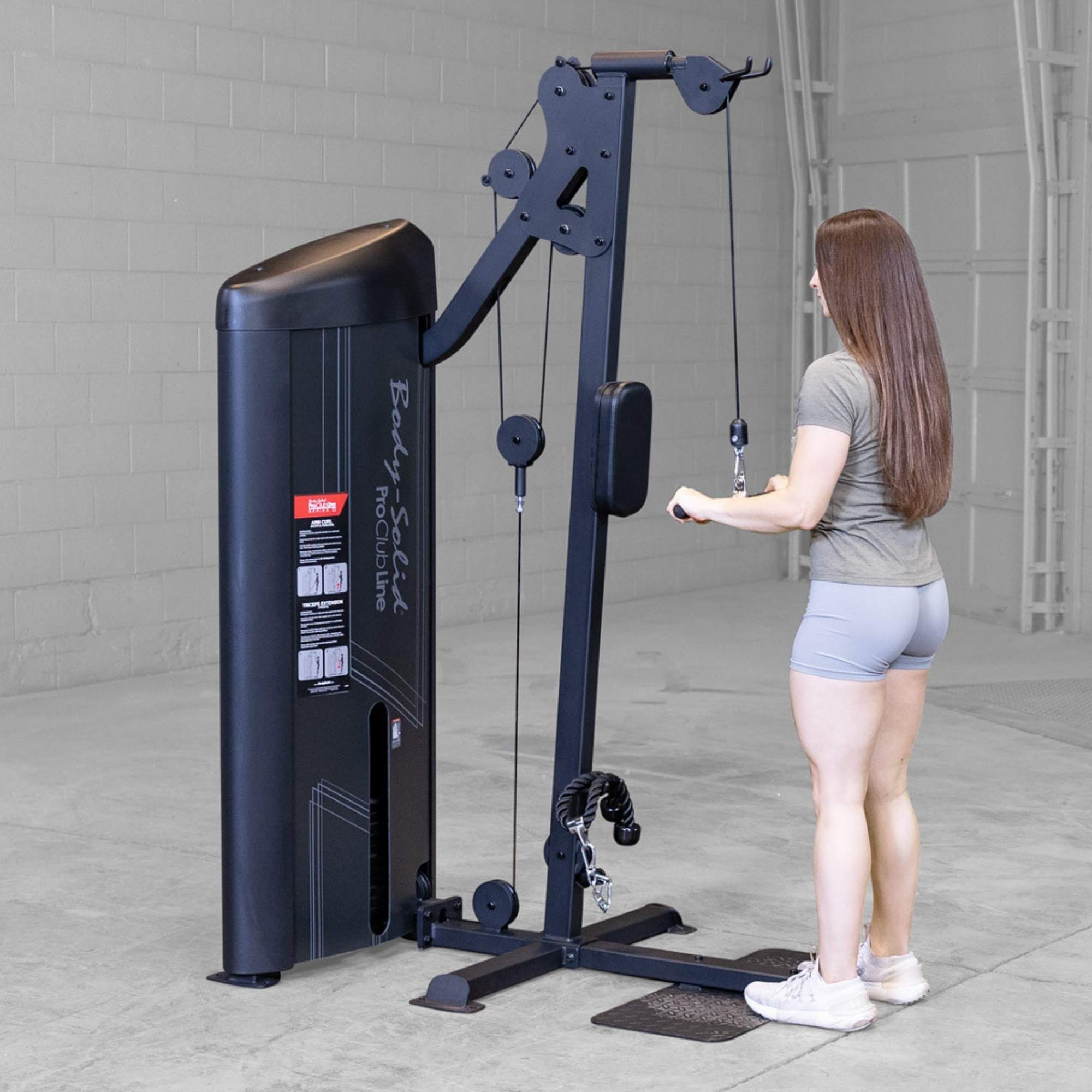 Body-Solid Pro ClubLine Series 2 Biceps Triceps S2BTPX Back view of woman preparing for a cable pushdown exercise, holding the straight handle attachment on a tall cable machine.