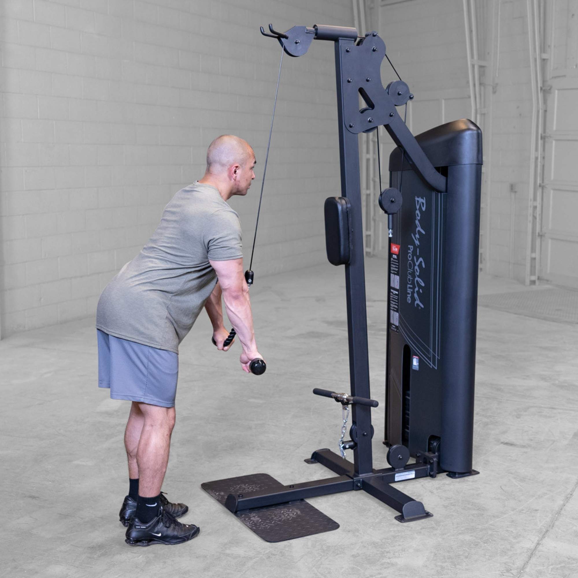Body-Solid Pro ClubLine Series 2 Biceps Triceps S2BTPX Man bent slightly forward performing cable tricep pushdowns on a Body-Solid cable machine in a concrete-floor gym.