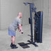 Body-Solid Pro ClubLine Series 2 Biceps Triceps S2BTPX Man in athletic gear finishing a cable tricep pushdown on a tall black pulley machine in a minimal gym space.