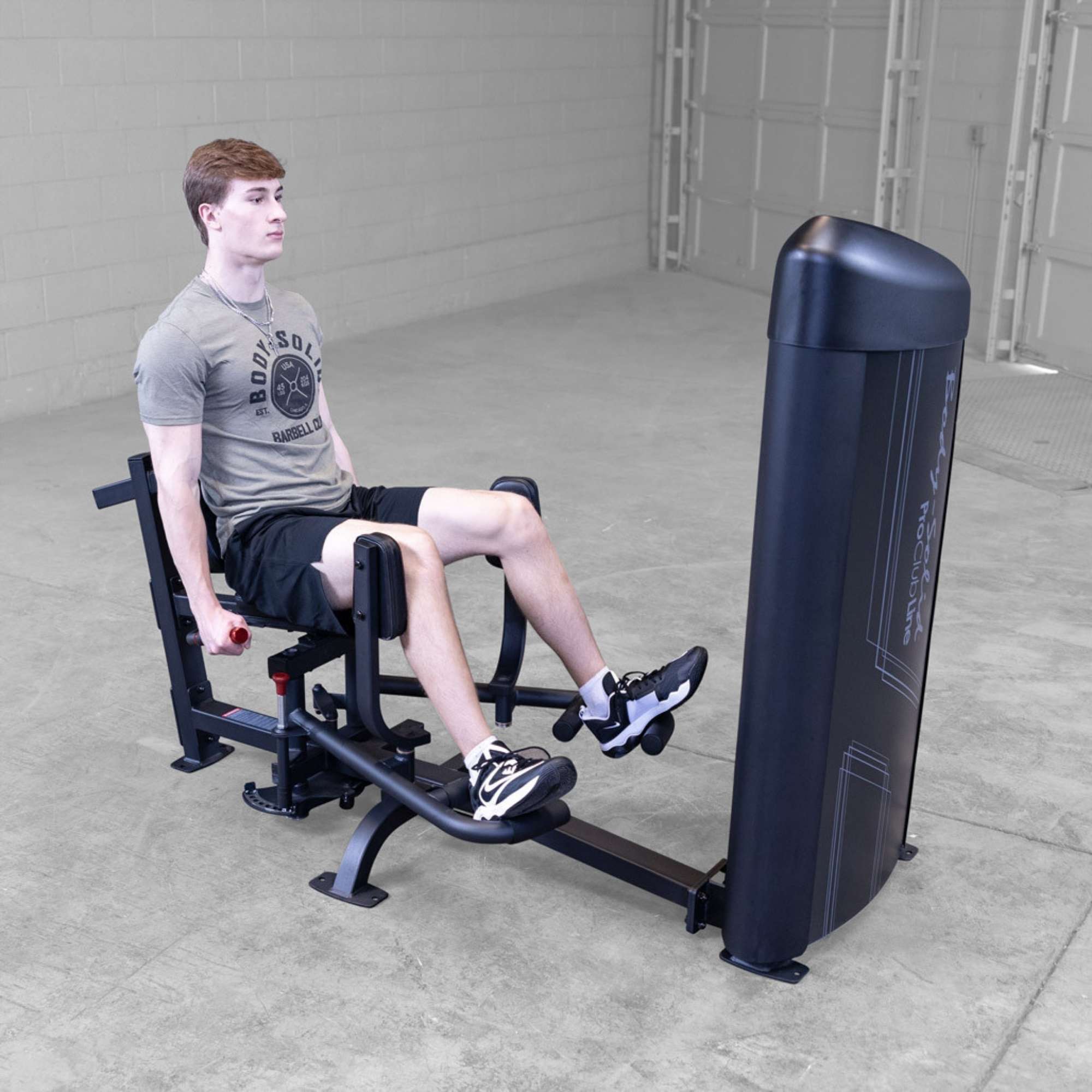 Body-Solid Pro ClubLine Series 2 Inner Outer Thigh S2IOTX Back view of man performing seated hip abduction exercise on a Body-Solid machine inside a spacious gym