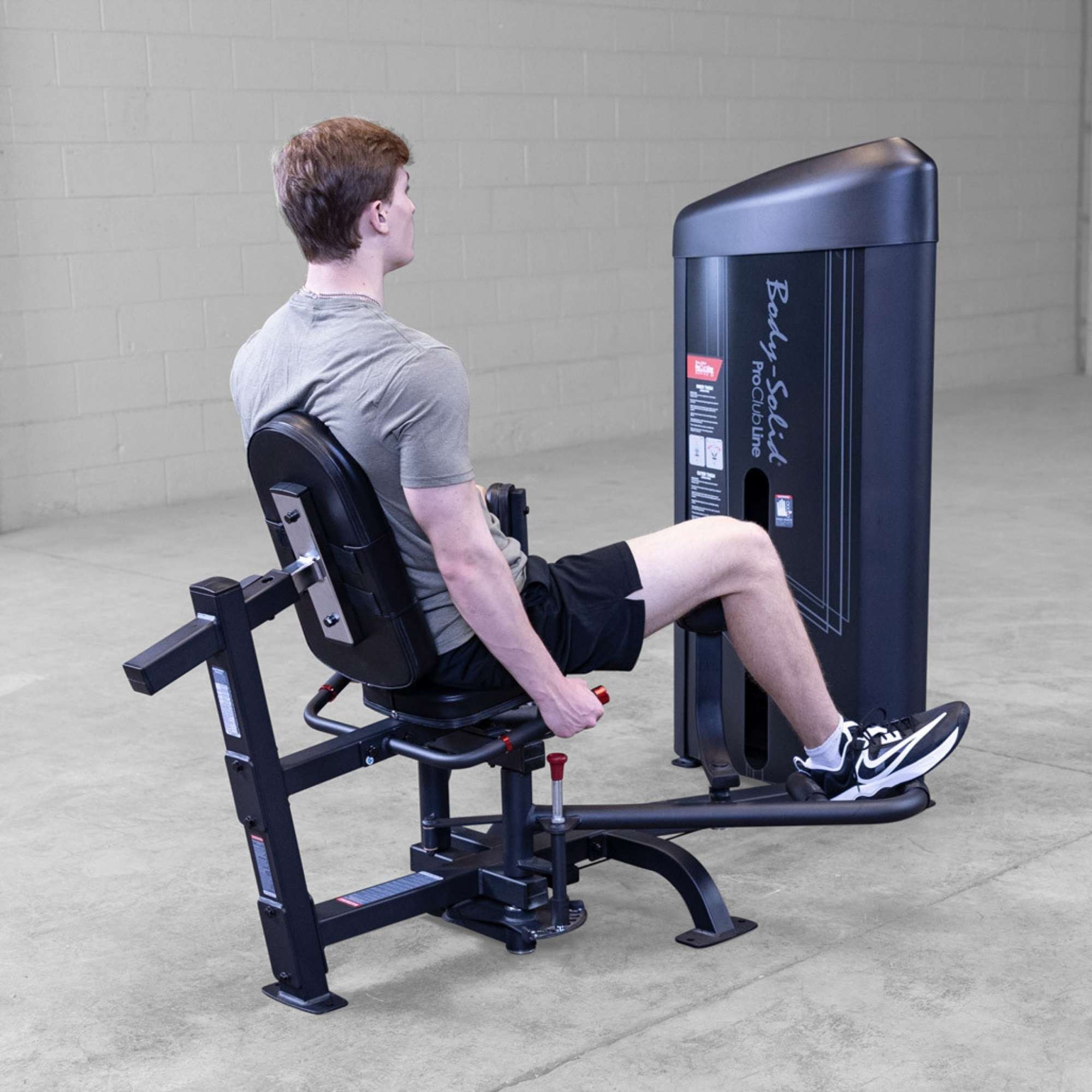 Body-Solid Pro ClubLine Series 2 Inner Outer Thigh S2IOTX Man seated on hip abduction machine, preparing for leg abduction movement with pads pressed against thighs