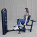 Body-Solid Pro ClubLine Series 2 Inner Outer Thigh S2IOTX Side view of woman performing a hip abduction movement on a seated leg machine in a gray industrial-style gym.