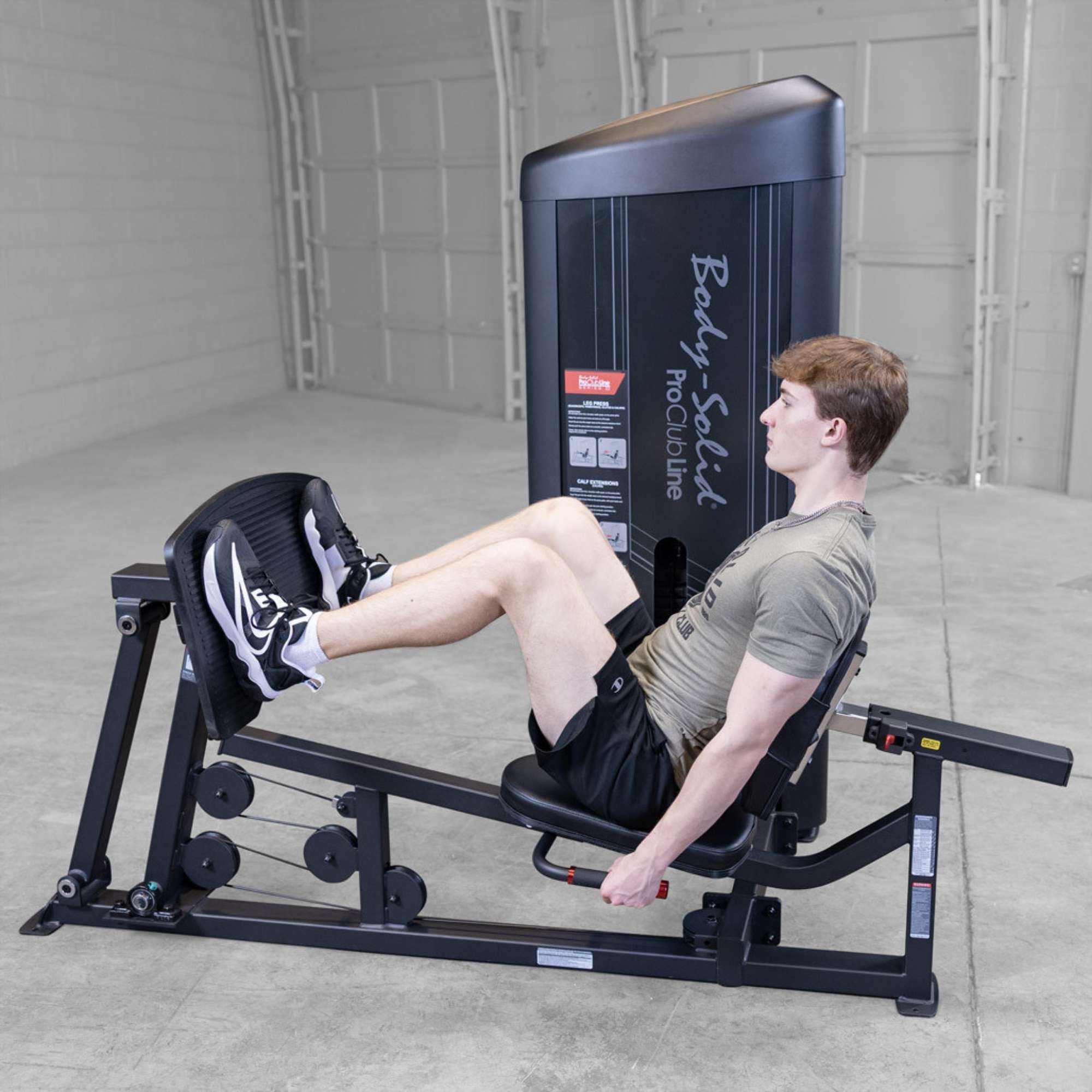 Body-Solid Pro ClubLine Series 2 Leg Calf Press S2LPCX Man performing seated leg press exercise on a Body-Solid ProClubLine machine with knees bent in starting position