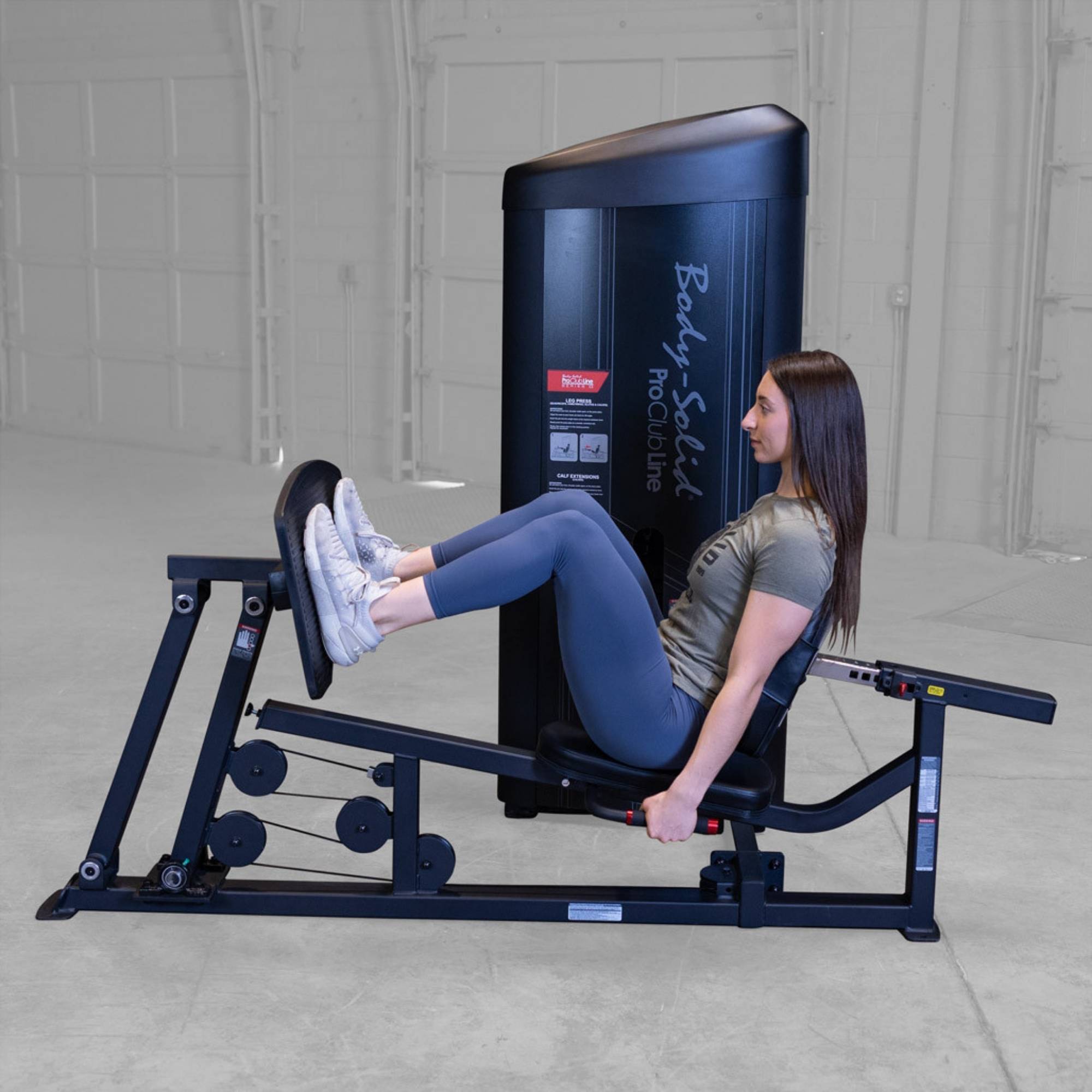 Body-Solid Pro ClubLine Series 2 Leg Calf Press S2LPCX Woman performing seated leg press reps with knees bent, pushing against textured footplate to activate leg muscles