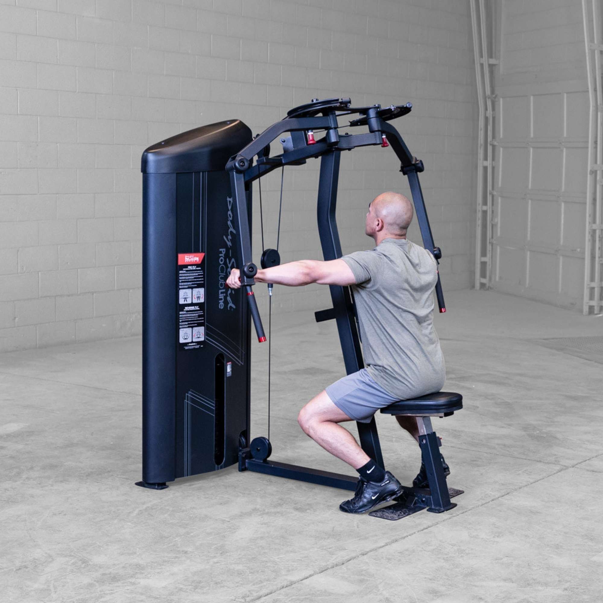 Body-Solid Pro ClubLine Series 2 Pec Delt S2PECX Man seated on Body-Solid ProClub Line machine holding handles in rear delt position before pulling outward