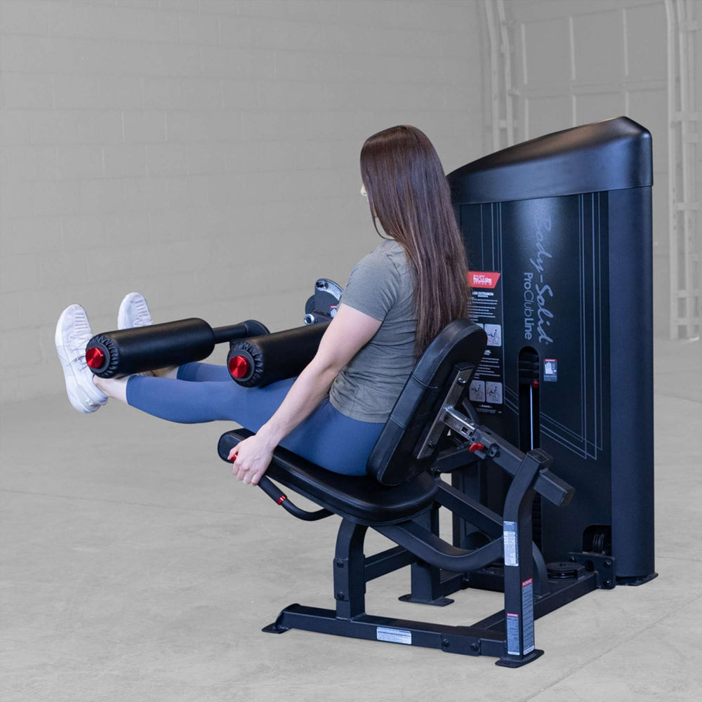 Body-Solid Pro Clubine Series 2 Leg Curl and Extension Back-angled view of woman performing leg extension exercise, showing proper machine positioning and foot placement S2LECX 
