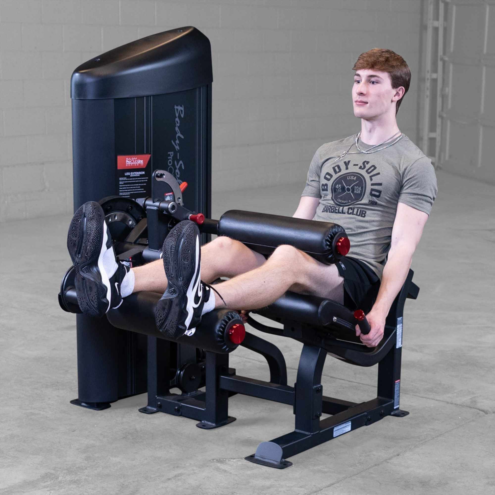 Body-Solid Pro Clubine Series 2 Leg Curl and Extension S2LECX Man performing a seated leg extension on the black machine, demonstrating the top position of the exercise 