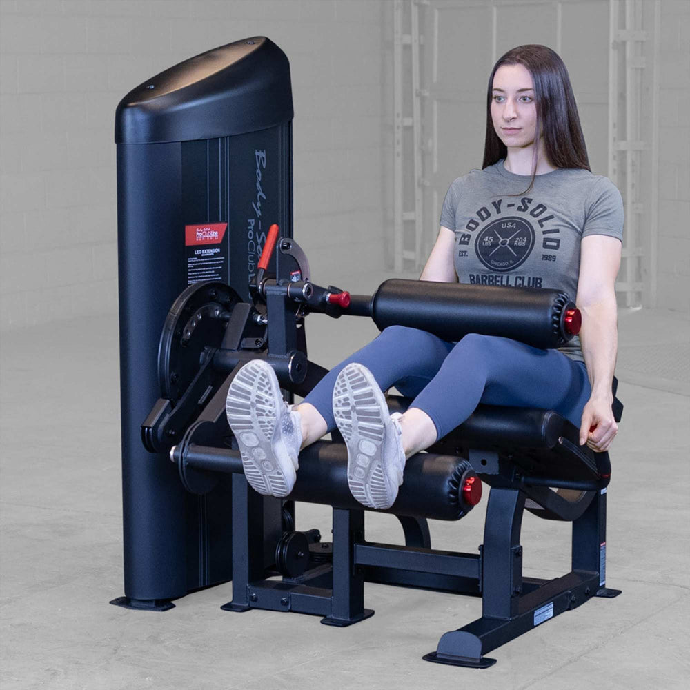 Body-Solid Pro Clubine Series 2 Leg Curl and Extension S2LECX Woman performing a seated leg extension on the black machine, demonstrating the top position of the exercise 