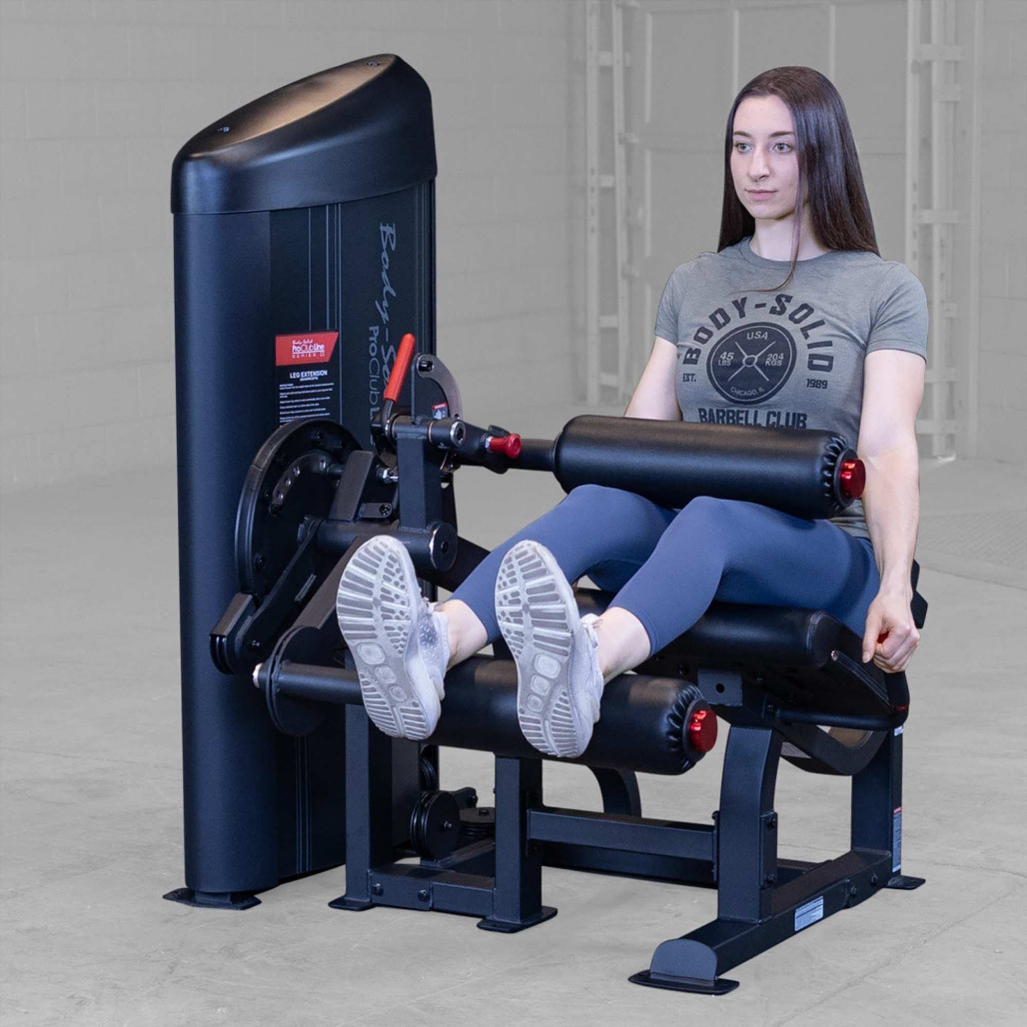Body-Solid Pro Clubine Series 2 Leg Curl and Extension S2LECX Woman performing a seated leg extension on the black machine, demonstrating the top position of the exercise 