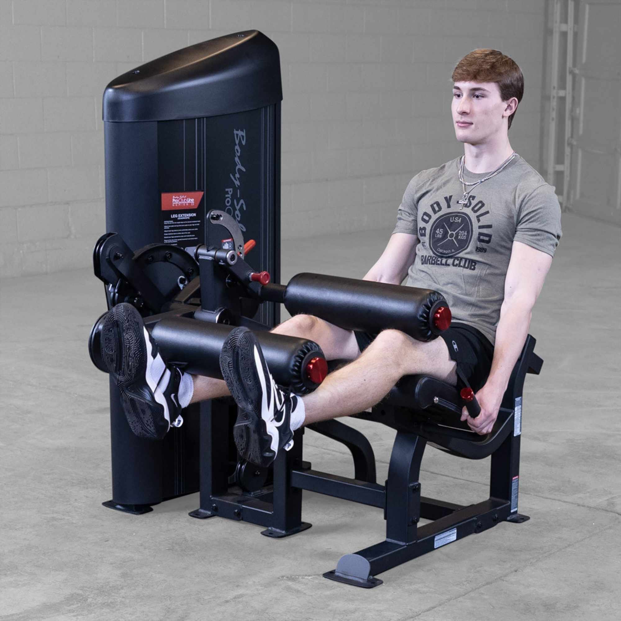Body-Solid Pro Clubine Series 2 Leg Curl and Extension S2LECX Young man Performing controlled return phase of the leg extension exercise in a gym 