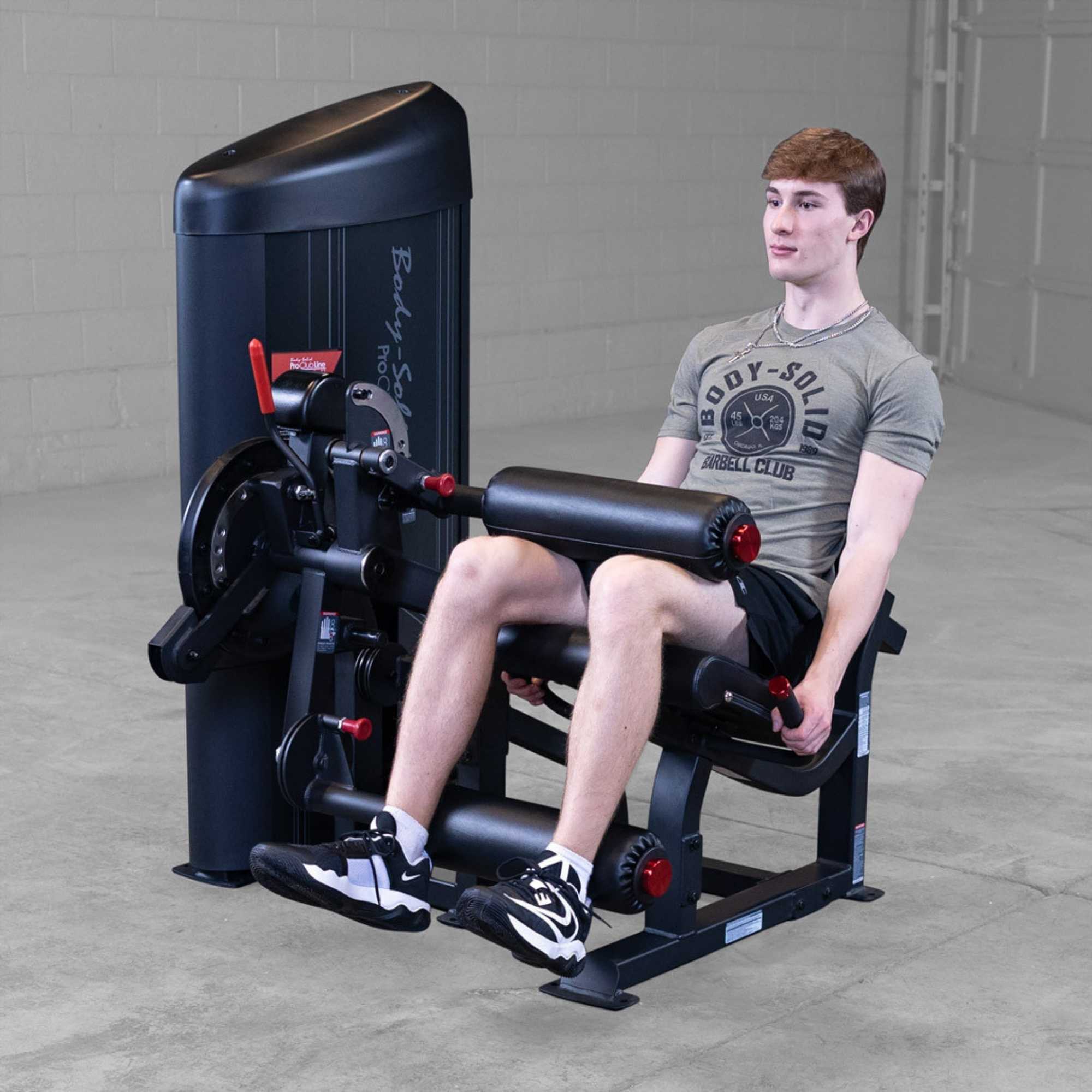 Body-Solid Pro Clubine Series 2 Leg Curl and Extension S2LECX  Young man seated, demonstrating the leg extension exercise in a gym setting 