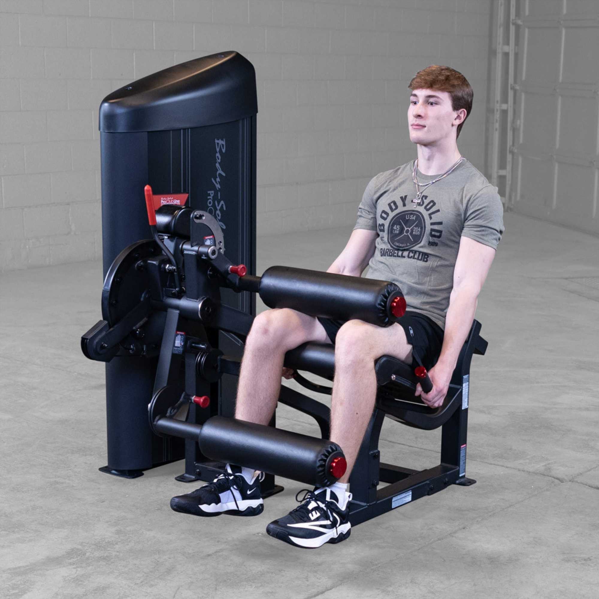 Body-Solid Pro Clubine Series 2 Leg Curl and Extension S2LECX  Young man seated  in a gym, with the machine ready for the leg extension exercise 
