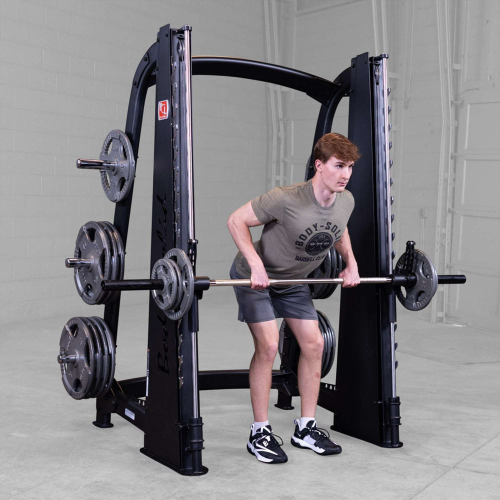 Body-Solid Proclub Counter Balanced Smith Machine SCB1000B A man performing a bent-over barbell row on a Smith machine while standing in a gym
