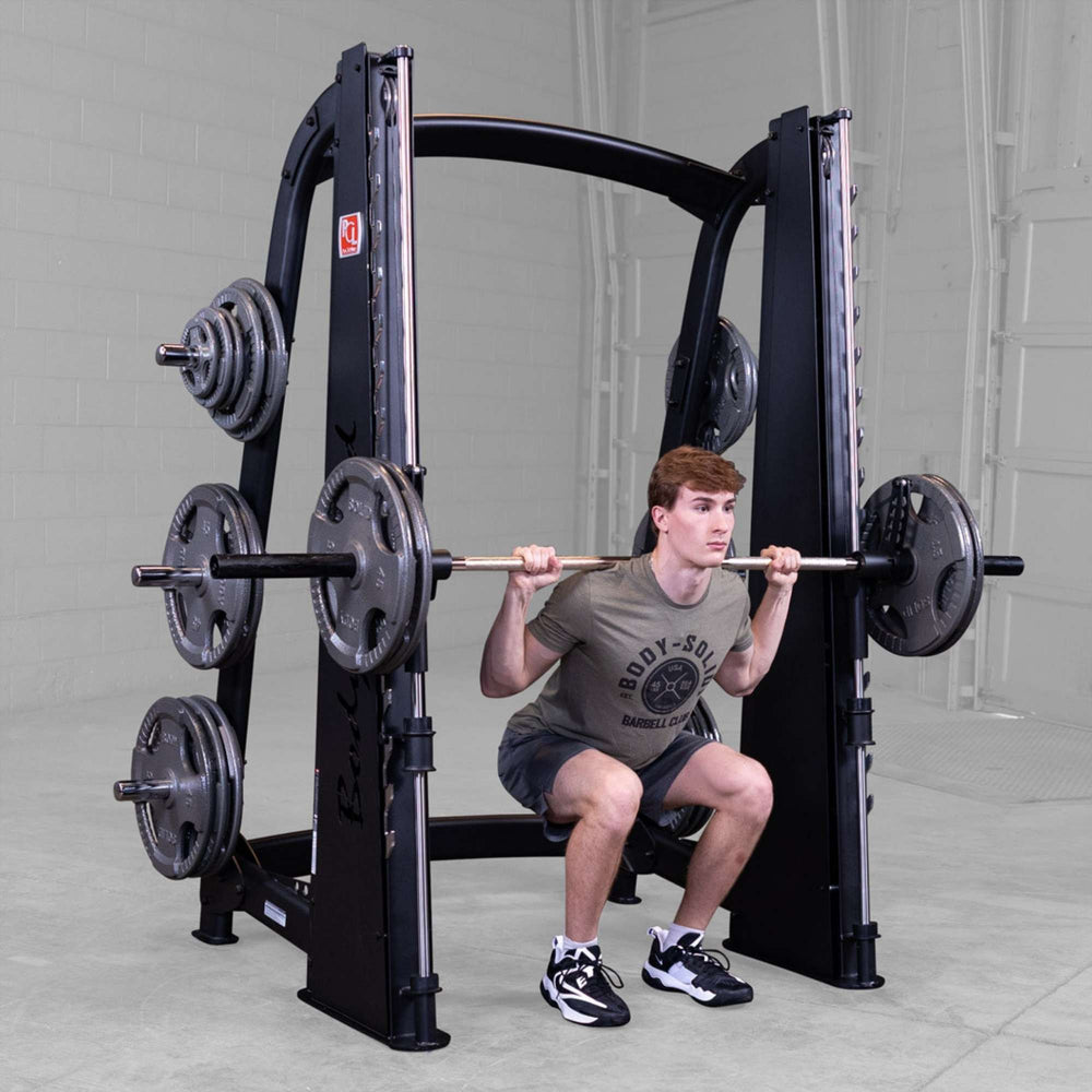 Body-Solid Proclub Counter Balanced Smith Machine SCB1000B Man performing a Smith machine squat with a loaded barbell in a gym.
