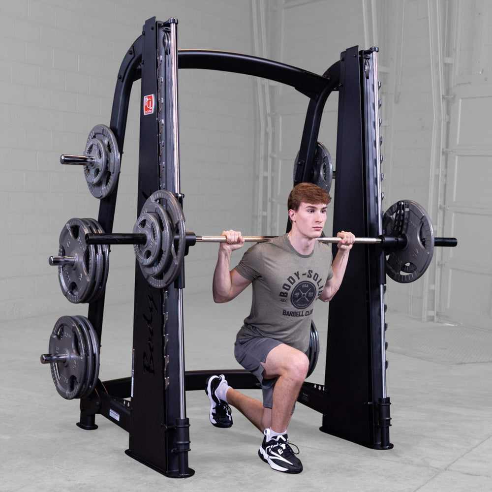 Body-Solid Proclub Counter Balanced Smith Machine SCB1000B Man performing a barbell reverse lunge on a Smith machine inside a gym.

