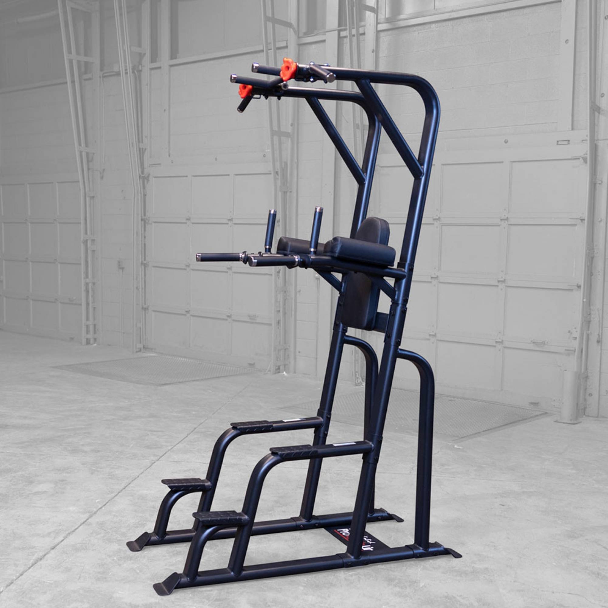 Body-Solid Proclub Vertical Knee Raise SVKR1000BX Full view of a tall black power tower exercise station in a large warehouse-style gym.