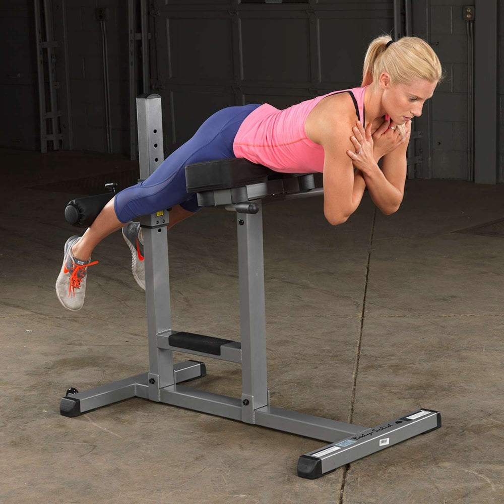 Body-Solid Roman Chair GRCH322B A woman demonstrating the forward-flexed position of a back extension in gym